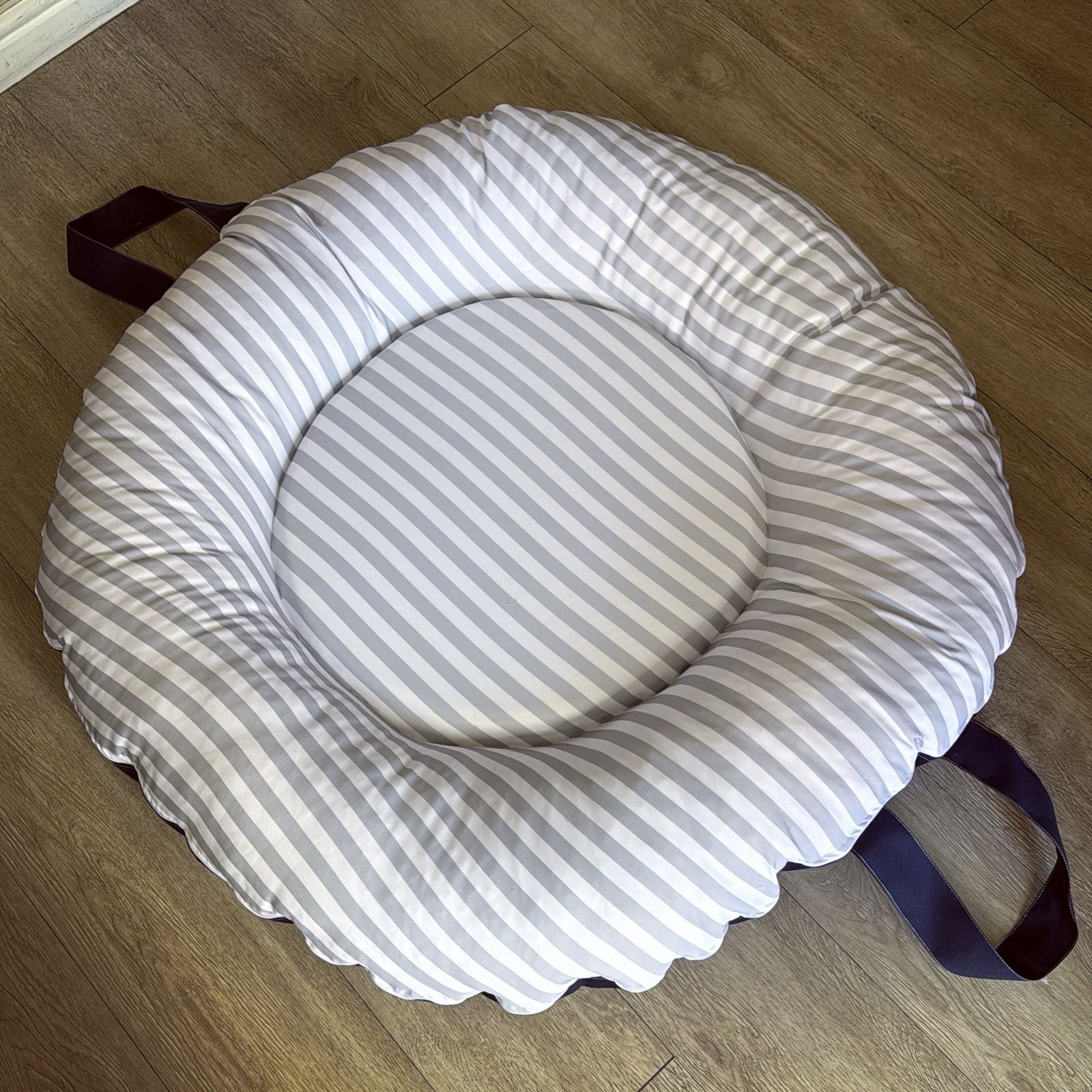 Round cushion with striped pattern on a wooden floor