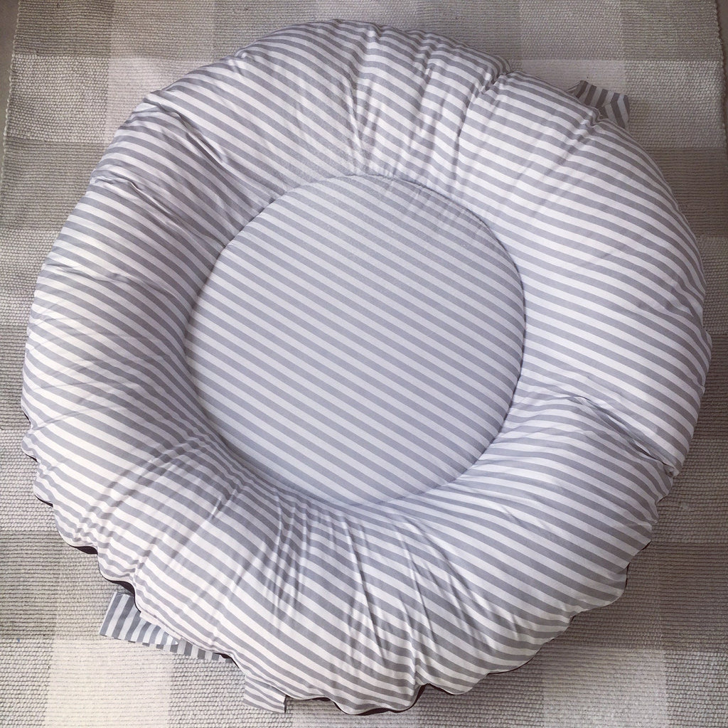 Round gray and white striped cushion on a textured surface