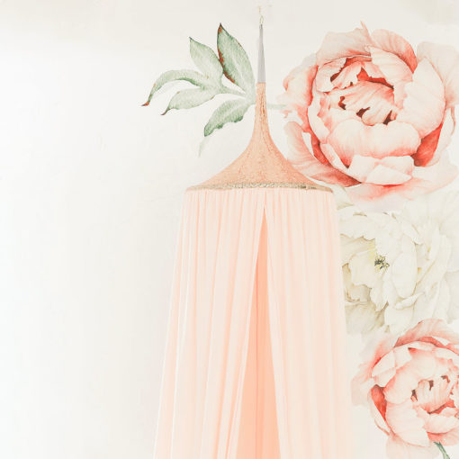 A pink hanging tent canopy with floral designs, set up in a room with a white background. It is positioned above a cream-colored feeding chair with a rose gold accent.