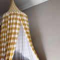 Yellow and white checkered curtain partially open on a gray wall.