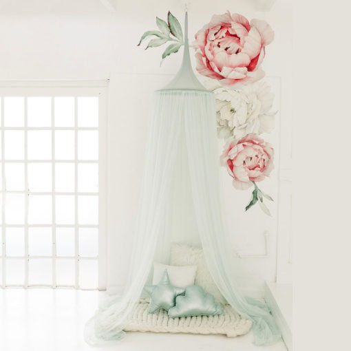 A moss green hanging tent canopy with a hoop diameter of 45cm, adorned with artificial pink roses and green foliage, set up in a room with a white cushion and a small star-shaped pillow.