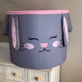 A large laundry basket with a cartoon bunny face design, predominantly gray with pink inner ears and a smiling face.
