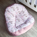 Pink baby seat cover with bunny pattern on a wooden floor