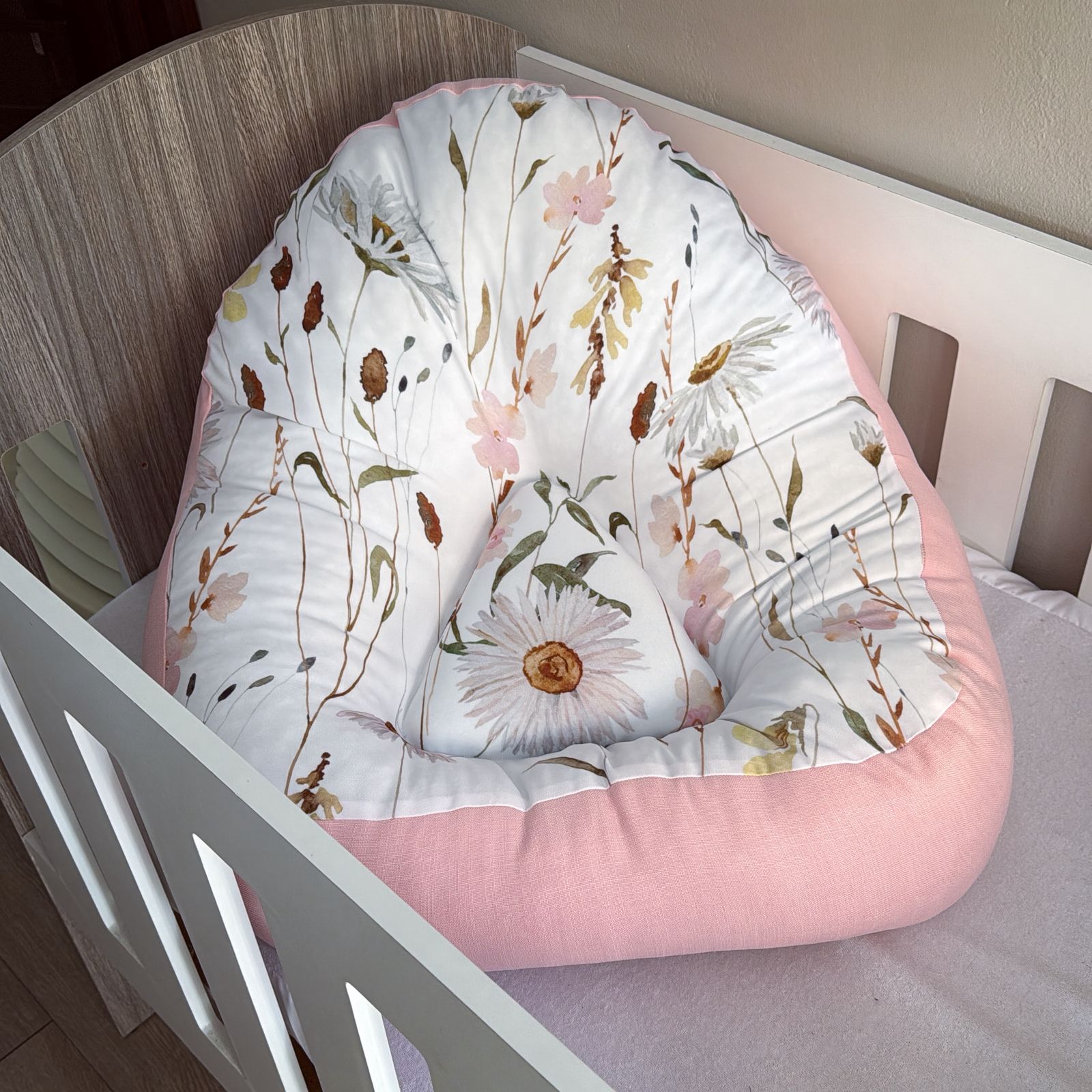Floral-patterned baby louncer in a crib