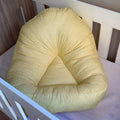 A yellow lounger with mustard dots pattern placed in a white crib.