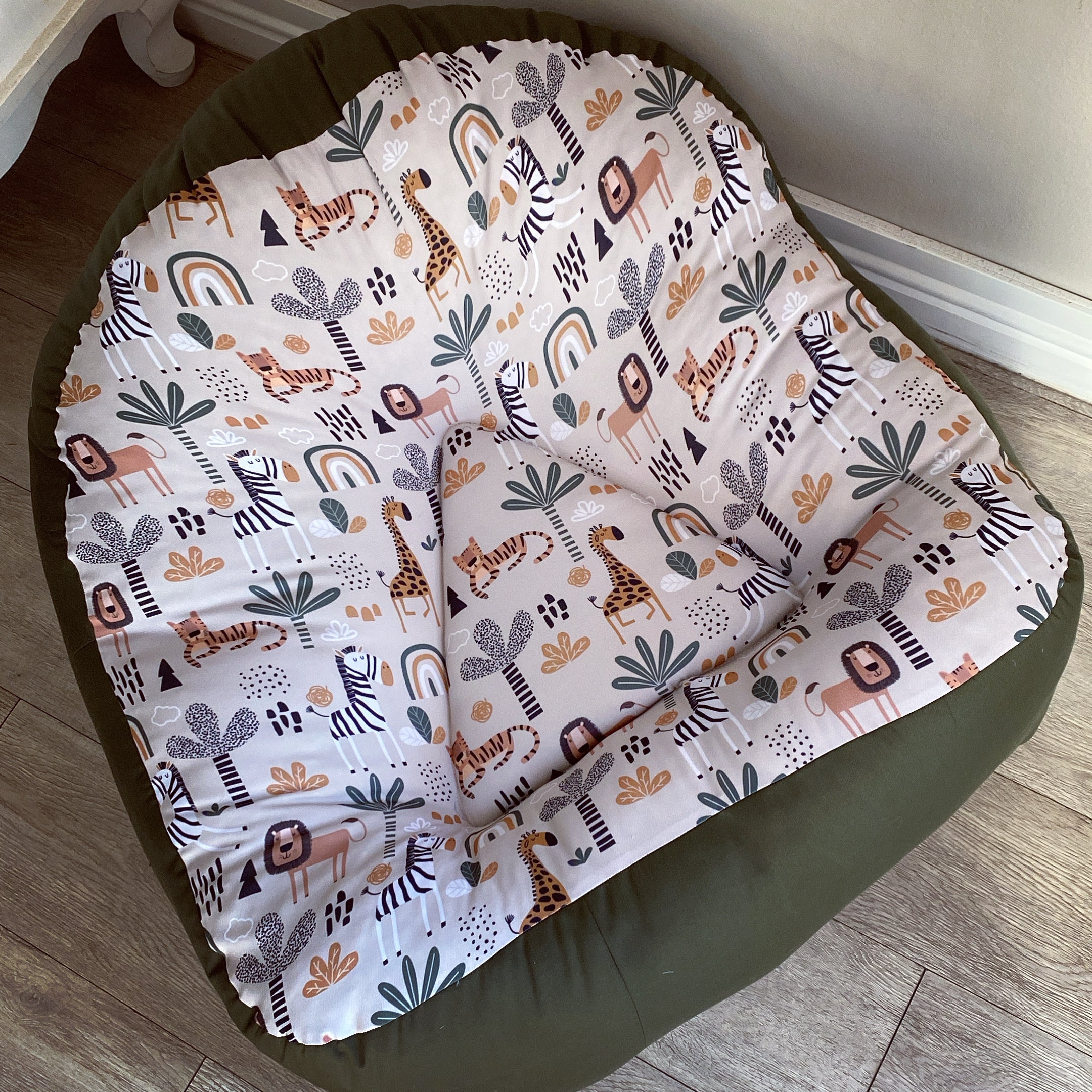 A bean bag chair with a safari animal print, primarily in shades of green and beige, with a soft, upholstered top and a sturdy, dark green base.