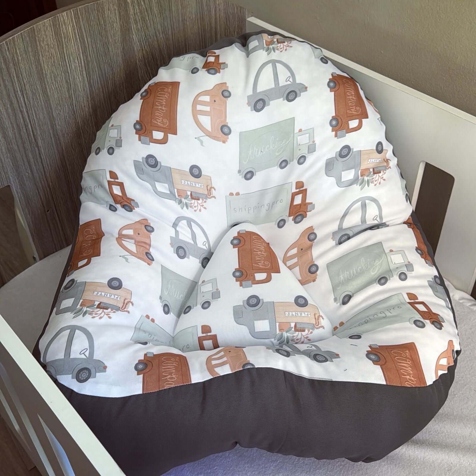 Baby bouncer with truck pattern in a crib