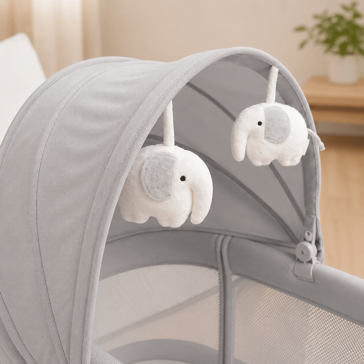 Gray crib with elephant-shaped hanging toys in a neutral setting