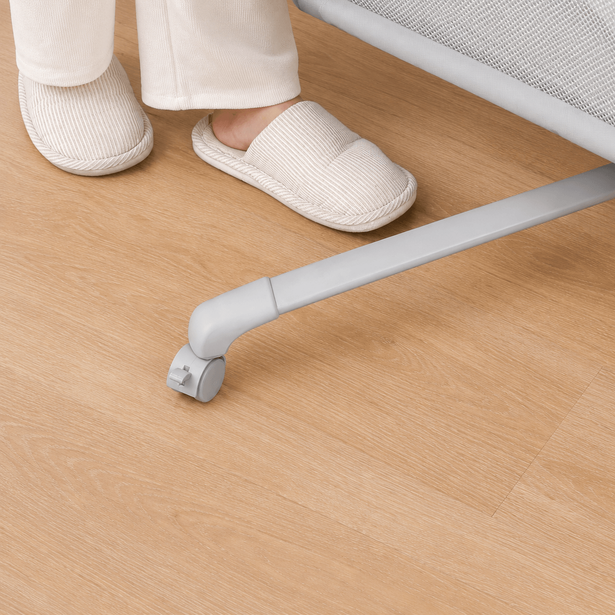 White slippers on a wooden floor with a chair leg in the foreground