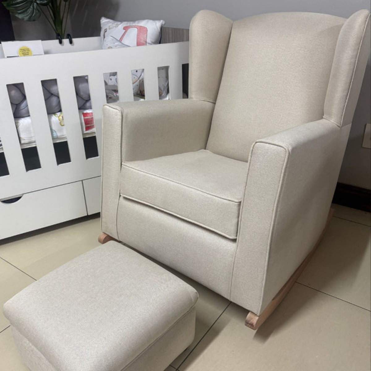 Beige armchair with matching ottoman in a room setting.