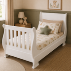 A white wooden toddler bed with a tall wingback headboard and slatted side rails, styled with safari-themed bedding and a green star pillow in a child's bedroom.