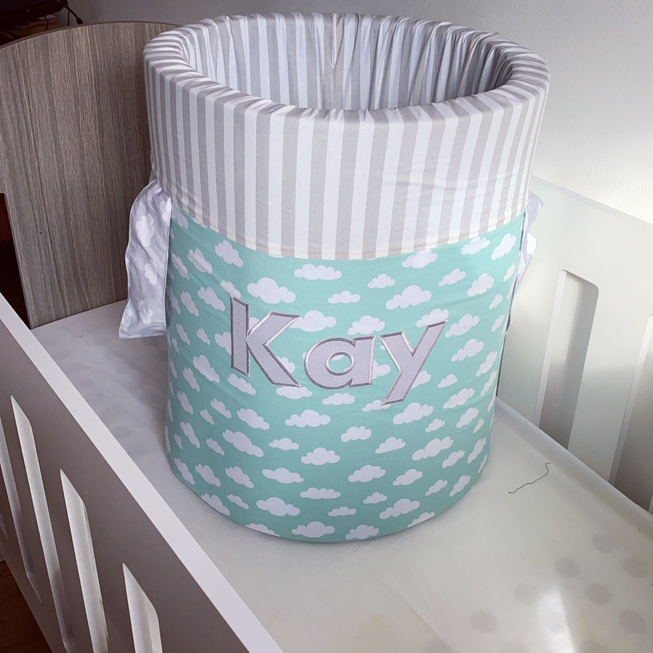 Children's laundry basket with cloud pattern and 'Kay' branding on a white surface.