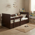 A dark brown wooden toddler bed with safety rails in a cozy, child-friendly bedroom. The bed is styled with a patterned duvet, a matching pillow, a teddy bear, and a star-themed mobile hanging from the ceiling.