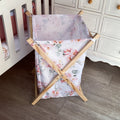 A wooden laundry basket with a pink floral pattern, featuring side handles and a five-point star base.