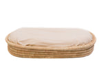 A beige woven basket with a soft mattress on top.