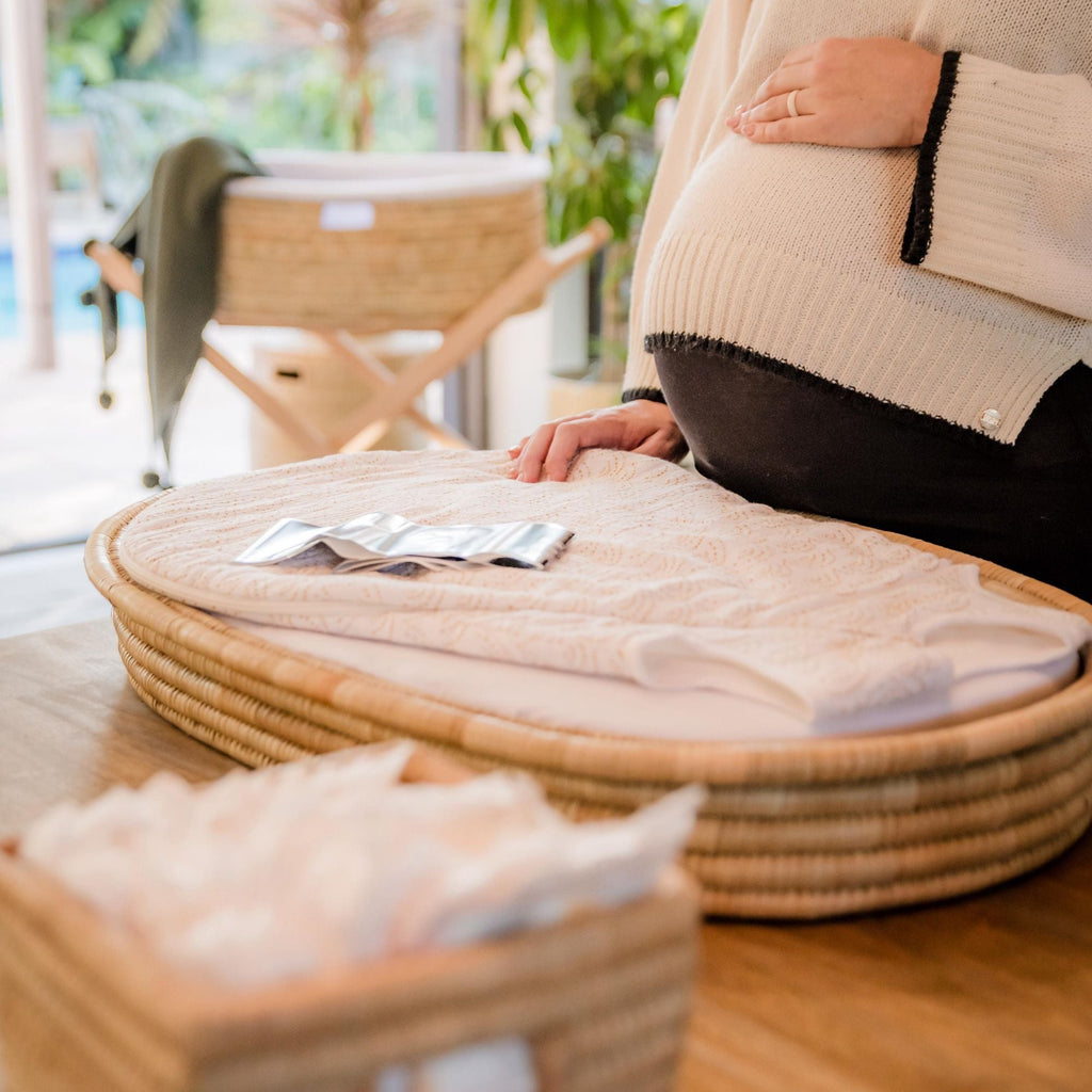Person sitting on a woven chair with a cushioned seat, surrounded by natural light.