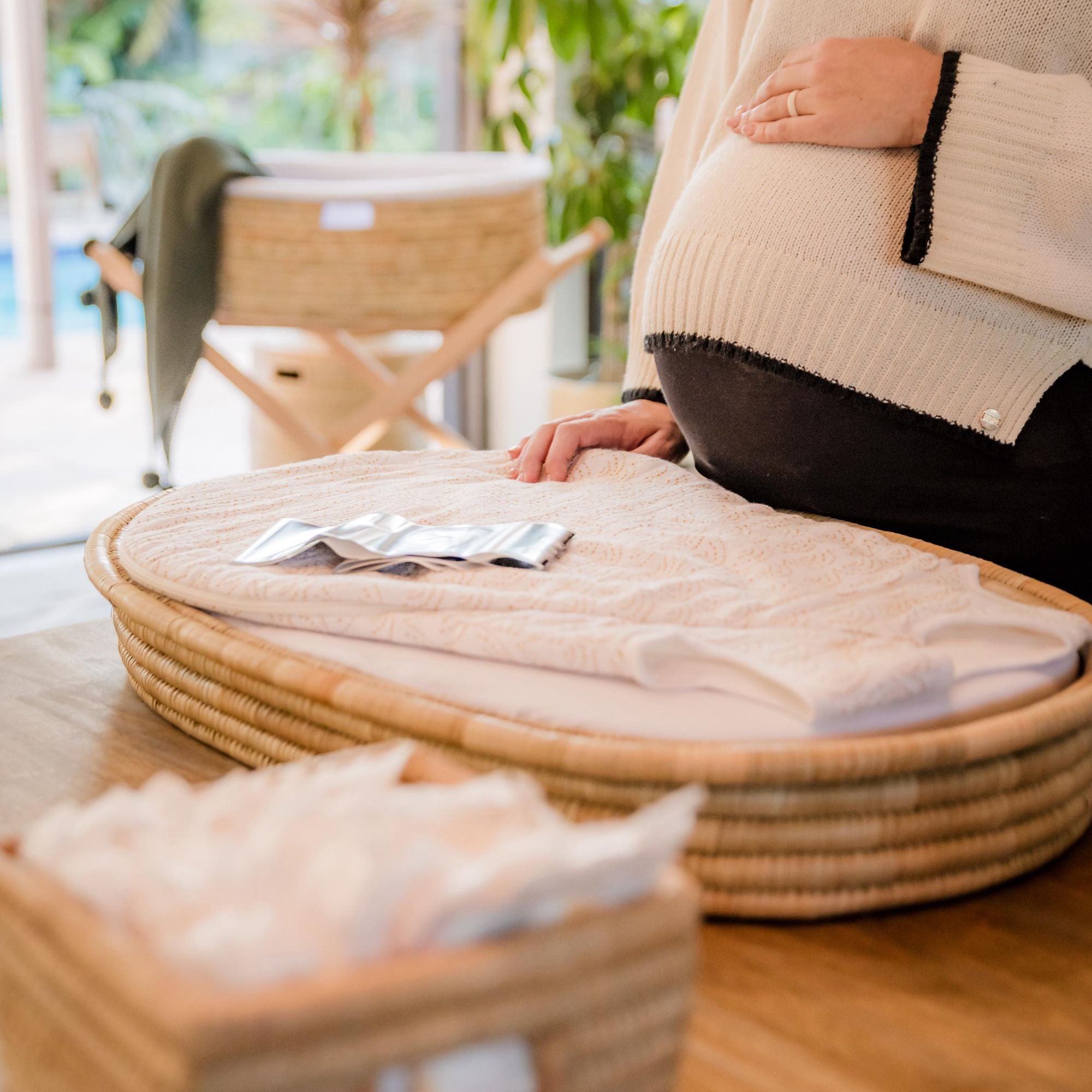 Person sitting on a woven chair with a cushioned seat, surrounded by natural light.