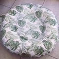 Round Doughnut - Green Leaf 01 cushion with green leaf pattern on a tiled floor