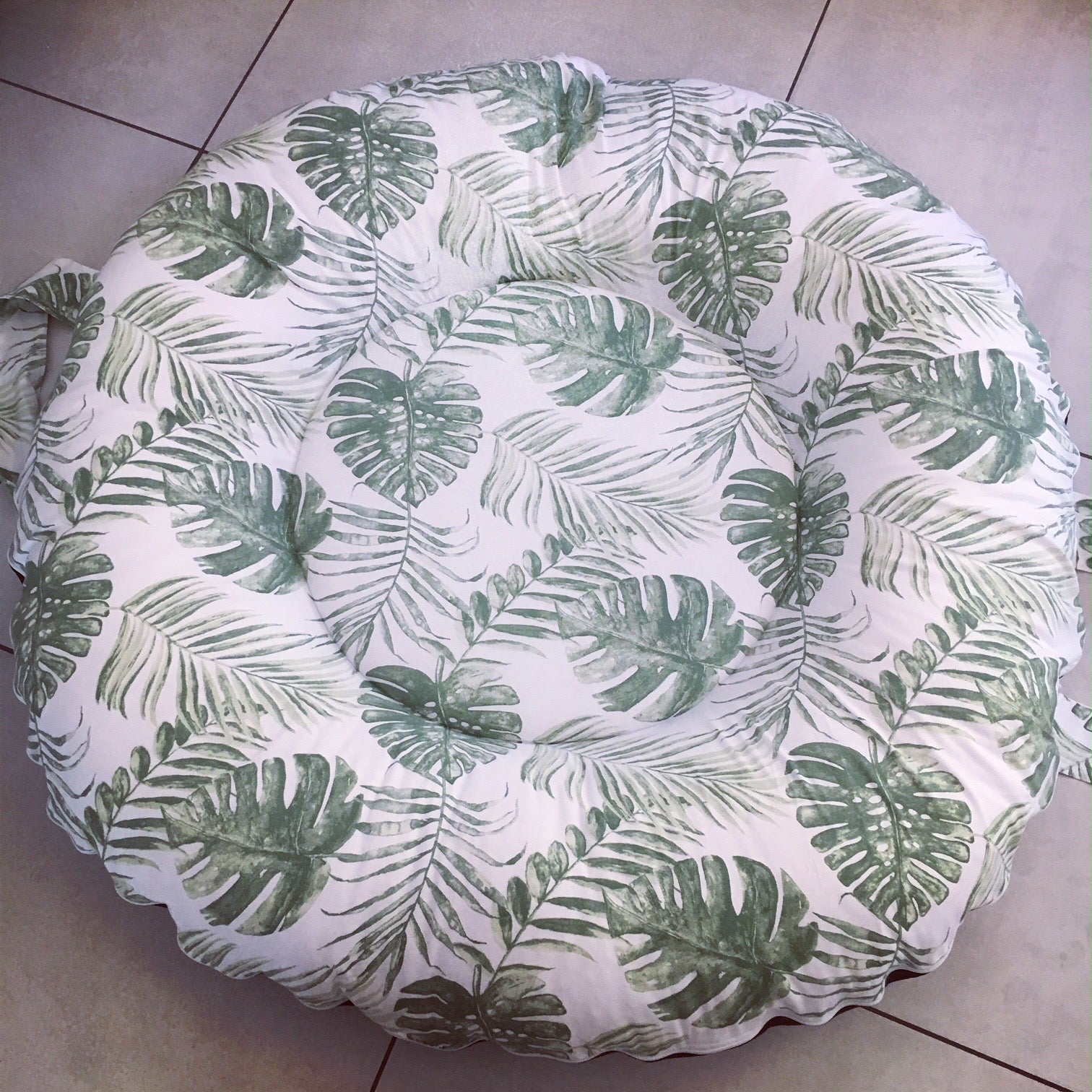 Round Doughnut - Green Leaf 01 cushion with green leaf pattern on a tiled floor
