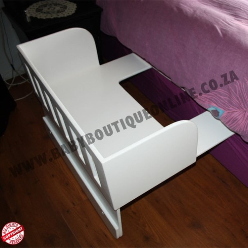 White baby crib with purple bedding on a wooden floor, branded 'Baby Boutique Online.co.za'.